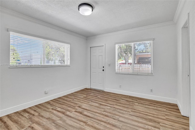 spare room with a textured ceiling, light wood finished floors, plenty of natural light, and crown molding