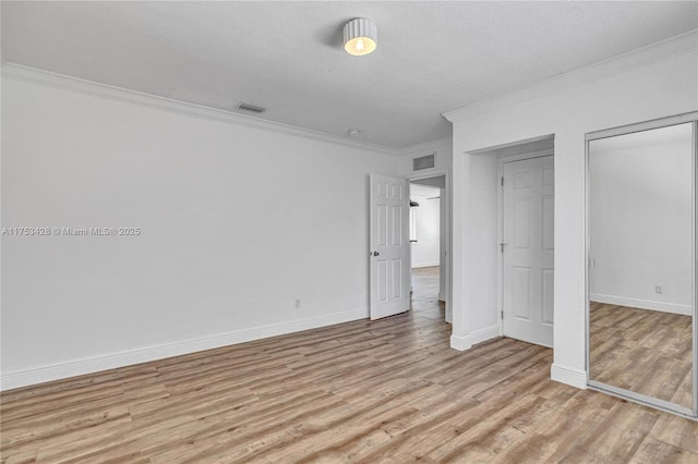 unfurnished bedroom with light wood-style flooring, visible vents, ornamental molding, and baseboards