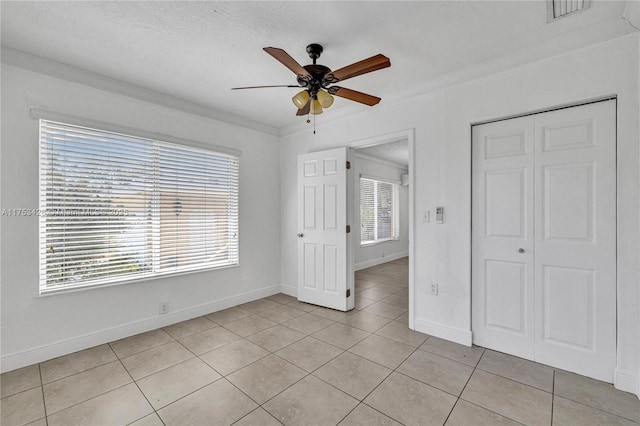 unfurnished bedroom featuring light tile patterned floors, visible vents, ornamental molding, a textured ceiling, and a closet