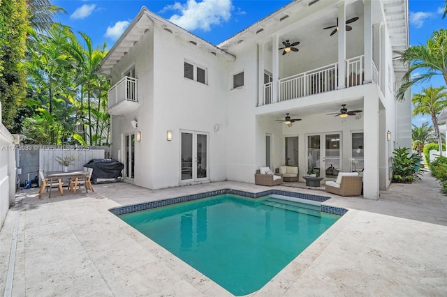 rear view of house with a balcony, outdoor lounge area, fence, french doors, and a patio area