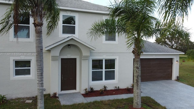 view of front of house with a garage, driveway, a shingled roof, and stucco siding