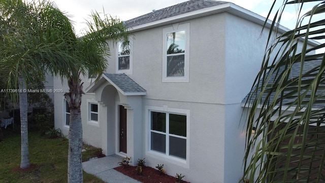 view of front of home featuring a shingled roof and stucco siding