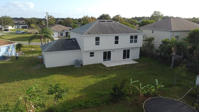 rear view of house featuring a patio, roof with shingles, fence, a yard, and central AC