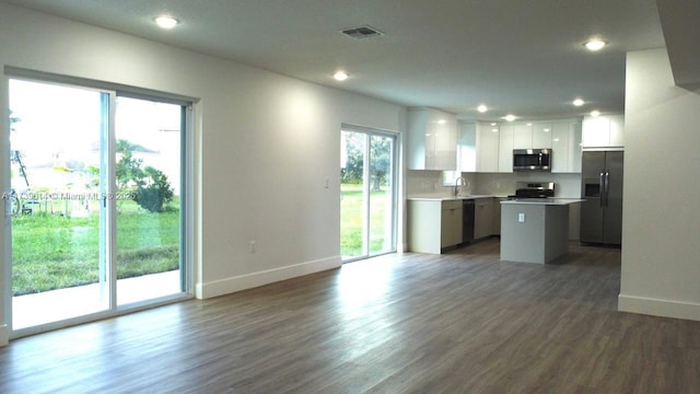 kitchen featuring a kitchen island, visible vents, white cabinetry, open floor plan, and appliances with stainless steel finishes