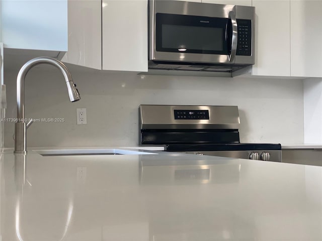 kitchen with appliances with stainless steel finishes, light countertops, white cabinets, and modern cabinets