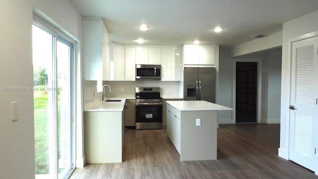 kitchen featuring a center island, light countertops, appliances with stainless steel finishes, dark wood-type flooring, and a sink