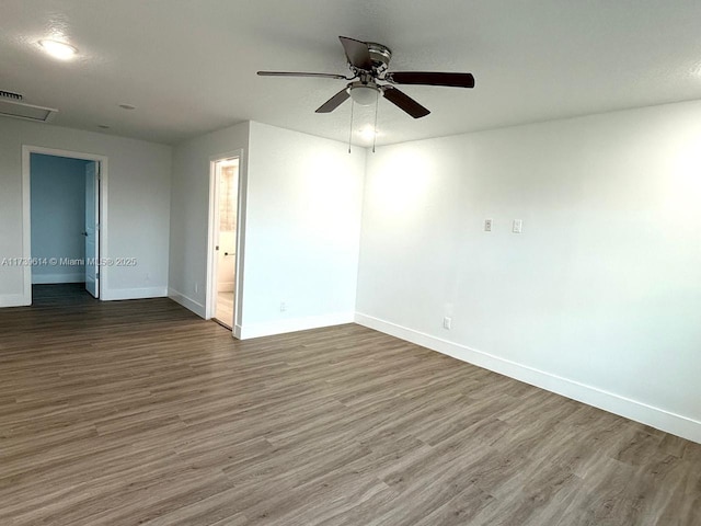 empty room with visible vents, ceiling fan, baseboards, and wood finished floors