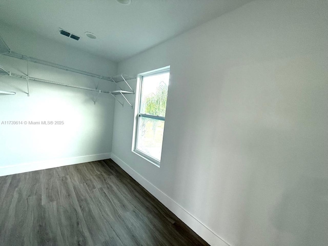 walk in closet with dark wood finished floors and visible vents