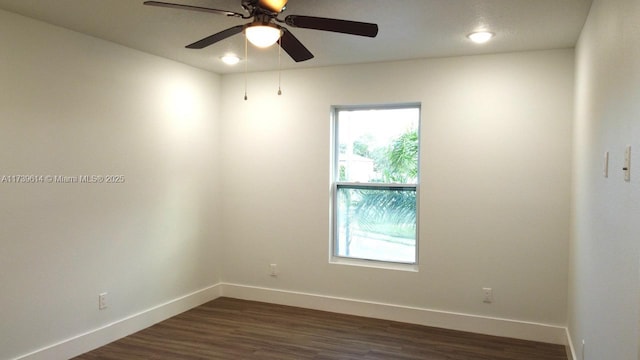 empty room featuring dark wood-style floors, ceiling fan, and baseboards