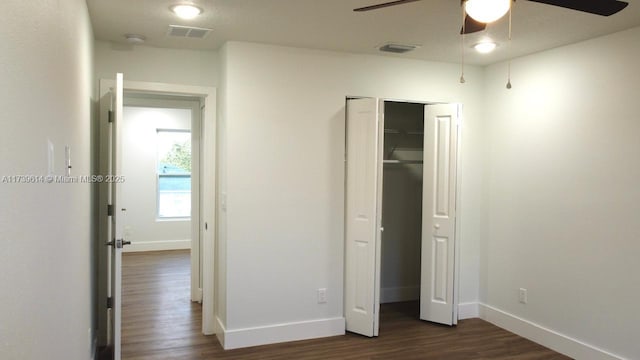 unfurnished bedroom with a closet, visible vents, dark wood finished floors, and baseboards