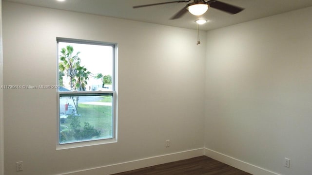 spare room with dark wood finished floors, a ceiling fan, and baseboards