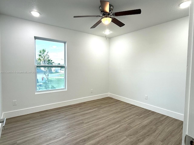 unfurnished room with wood finished floors, a ceiling fan, and baseboards