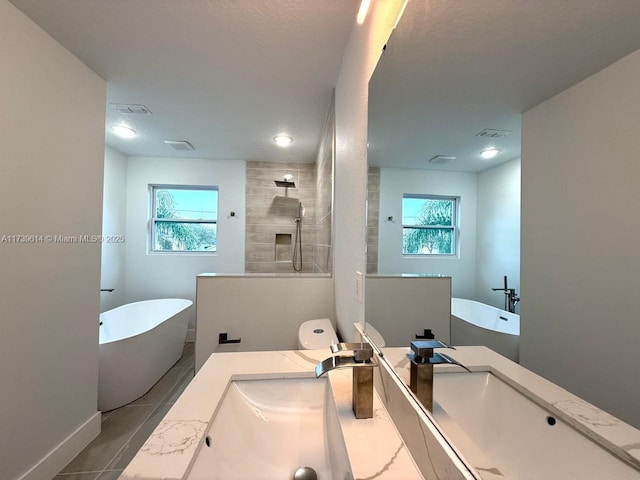 bathroom with a freestanding tub, visible vents, walk in shower, and vanity