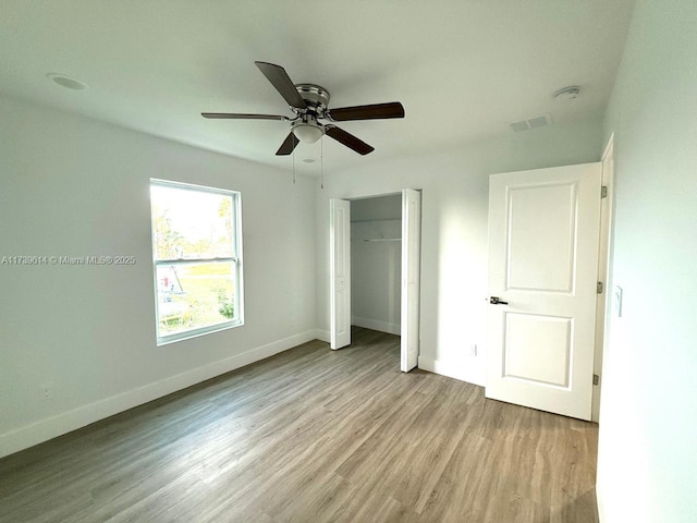 unfurnished bedroom featuring a closet, visible vents, ceiling fan, wood finished floors, and baseboards