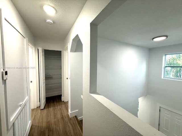 corridor featuring baseboards, visible vents, an upstairs landing, and wood finished floors