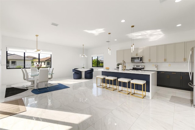 kitchen featuring a center island with sink, a breakfast bar area, marble finish floor, stainless steel appliances, and light countertops