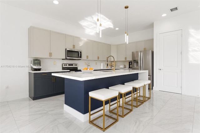 kitchen featuring a breakfast bar, light countertops, visible vents, appliances with stainless steel finishes, and a sink