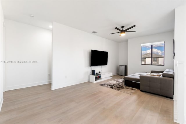 living room with light wood-style floors, ceiling fan, visible vents, and baseboards