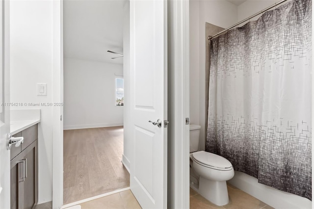 bathroom featuring toilet, curtained shower, vanity, and baseboards