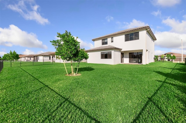 rear view of house featuring stucco siding, a fenced backyard, and a yard