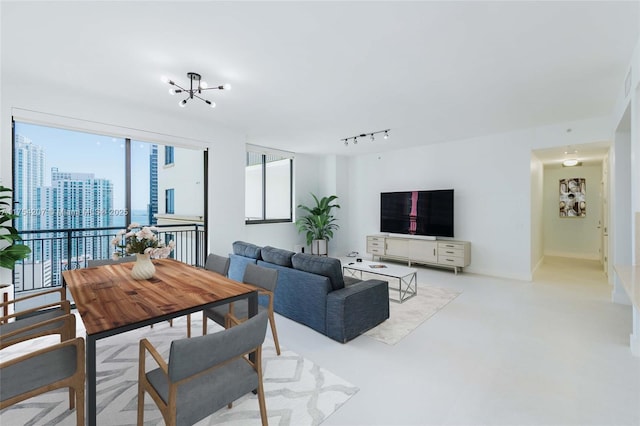 living area featuring a city view, a notable chandelier, finished concrete floors, track lighting, and baseboards