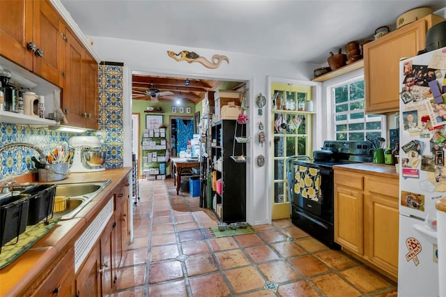 kitchen featuring ceiling fan, black range with electric stovetop, a sink, freestanding refrigerator, and tasteful backsplash