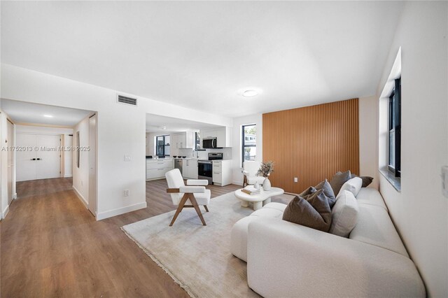 living room with light wood finished floors, baseboards, and visible vents