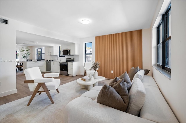 living area with baseboards, visible vents, and light wood-style floors