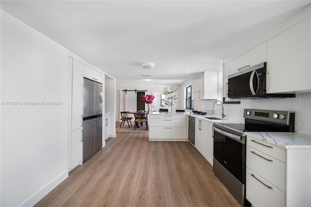 kitchen featuring stainless steel appliances, white cabinetry, a sink, and tasteful backsplash