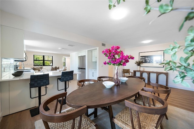 dining space with light wood-style flooring, visible vents, and baseboards