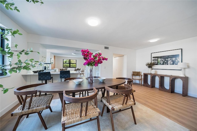 dining area featuring light wood-type flooring, visible vents, and baseboards