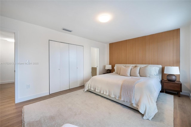 bedroom featuring baseboards, a closet, visible vents, and wood finished floors