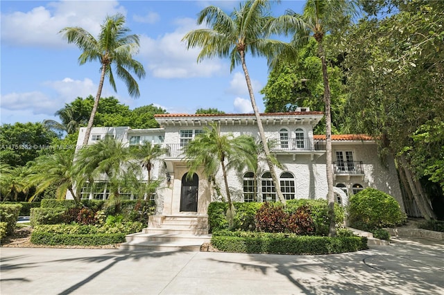 mediterranean / spanish home featuring a tiled roof, a balcony, and stucco siding