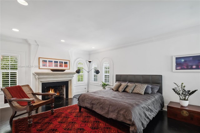 bedroom featuring a lit fireplace, multiple windows, and crown molding