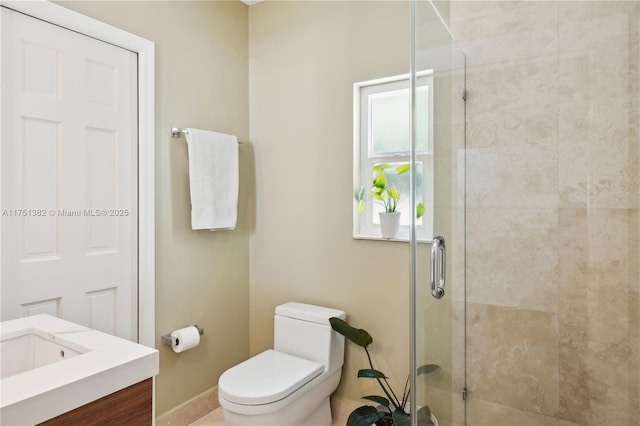 bathroom with toilet, a shower stall, baseboards, and vanity