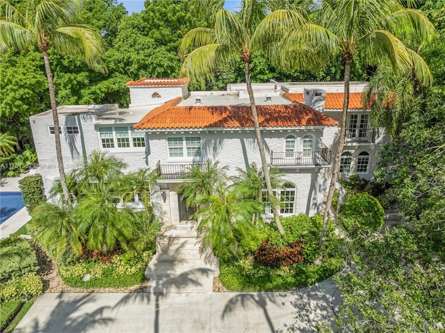 mediterranean / spanish-style house with a tile roof, a balcony, and stucco siding