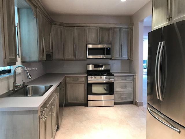 kitchen featuring light tile patterned floors, stainless steel appliances, a sink, and light countertops