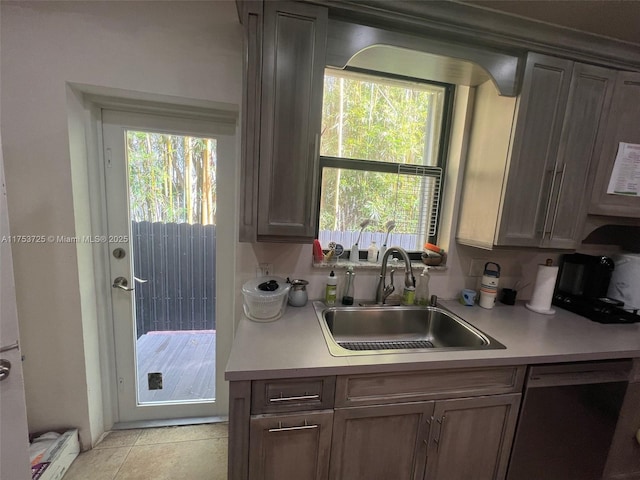 kitchen featuring a sink, dishwashing machine, and light countertops