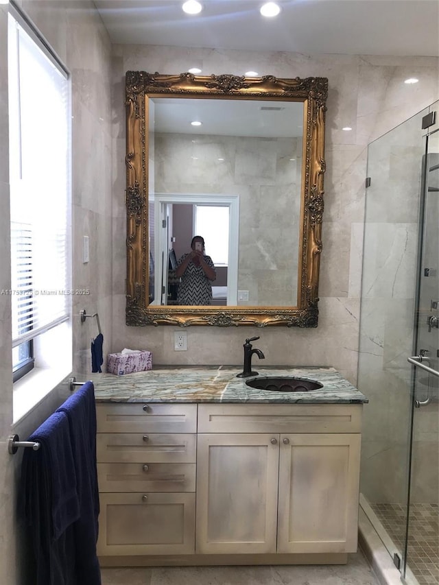 bathroom featuring a stall shower, plenty of natural light, vanity, and tile walls