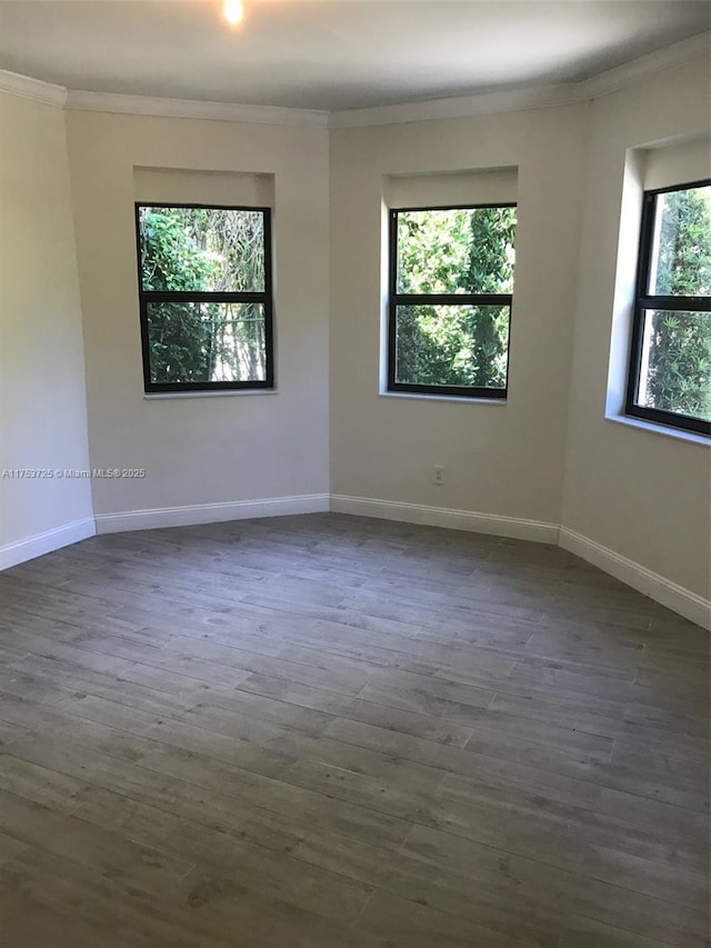 unfurnished room with dark wood-style floors, baseboards, and ornamental molding