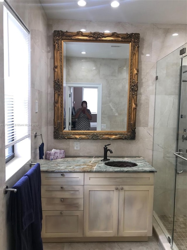 bathroom with tile walls, a shower stall, and vanity