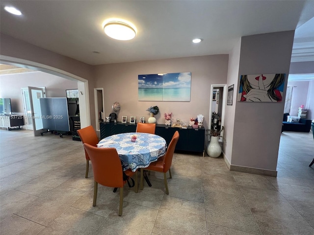 dining room featuring baseboards, recessed lighting, and arched walkways