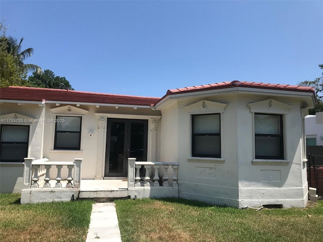back of house with stucco siding and a tiled roof