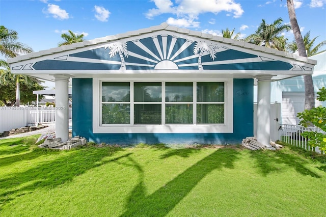 back of property featuring stucco siding, fence, and a yard