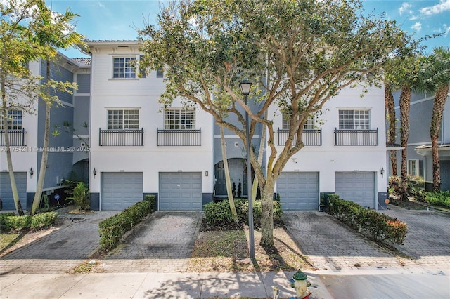 townhome / multi-family property with decorative driveway, a garage, and stucco siding