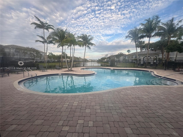 pool with a patio area and fence