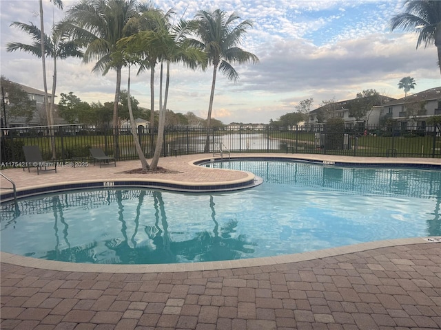 community pool with a patio area and fence