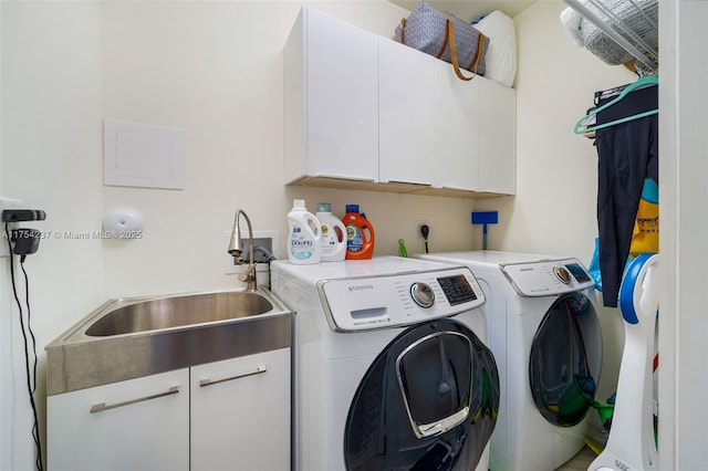 clothes washing area featuring cabinet space, separate washer and dryer, and a sink