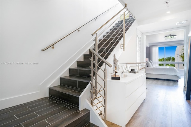 stairway with wood finished floors, visible vents, and baseboards