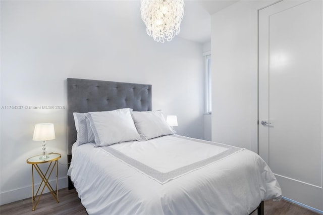 bedroom featuring a notable chandelier, baseboards, and wood finished floors